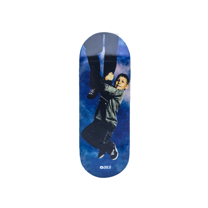 Deck fingerboard Galo Serie Malcolm Dewey, ilustración de Dewey colgando de una barra sobre cielo azul